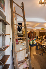Tall vintage quilt ladder with distressed wood and white paint remnants.