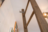 Aged brown wood and industrial metal bracket detail on the vintage quilt ladder.
