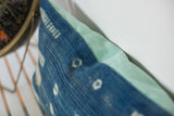 Textured indigo batik fabric detail, sun-faded patterns, and mint green linen pillow back.