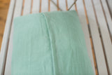 Detail of sea foam mint green European linen pillow back with white zigzag stitch.