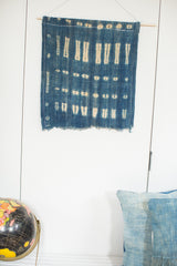 Frayed lower edge of the vintage indigo blue batik textile, showing light beige striping and dot patterns.