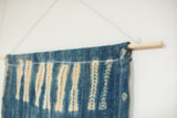 Wood dowel and hanging rope on vintage indigo batik textile.