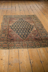 Antique Farahan Sarouk rug corner, cochineal red border, navy boteh and germinating plants, tattered edge.