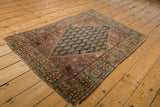 Antique Farahan Sarouk rug close-up, revealing navy boteh field, dusty red border, tattered edge.