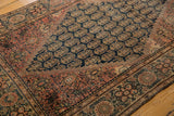 Dusty cochineal red floral border meets dark navy boteh field of antique Persian Farahan Sarouk.