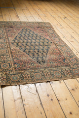Detail of the antique Farahan Sarouk rug's aged end, showing tatter and patterned border.