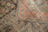 Distressed antique Malayer rug with worn texture, faded terracotta, and dark blue patterns.
