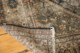 Distressed antique Malayer rug showing worn fringe, olive green pile, and hand-knotted foundation.