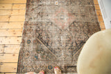 Distressed corner of an antique Mission Malayer rug, with frayed fringe and faded geometric motifs.