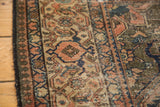 Distressed antique Malayer rug with worn coral, navy, and beige geometric patterns.