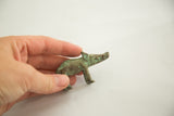 Vintage African bronze pig casting, displaying aged green patina held in hand.