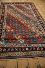 Caucasian rug corner: repeating floral motifs in red, blue, saffron, and intricate banded borders.
