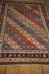 Antique Caucasian rug border detail with navy, cream, red, and yellow stylized floral and geometric bands.