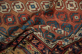 Textured fold of an antique Caucasian rug, revealing its deep navy border with geometric motifs.