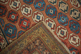 Intricate hand-knotted reverse and geometric red, blue, cream motifs of an antique Caucasian rug.