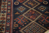 Crossing geometric medallions with stylized flowers and pinwheels on a dark indigo antique Caucasian rug.