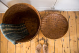 Round vintage rattan basket lid, warm brown, with distinct hand-woven pattern.