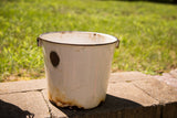White vintage enamel pail with a dark rim, showing rust patina at the base.