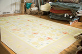 Vintage Dhurrie carpet with large scrolling floral design in yellow, blush, and light blue.