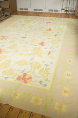 Corner of vintage Dhurrie carpet, featuring scrolling yellow, blush, blue flowers and a beige border.