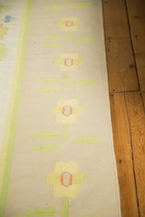Minimalist vintage Dhurrie with scrolling sunflower yellow and blush floral motifs.