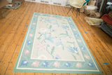 Vintage Minimalist Dhurrie corner: honeydew green border, pastel floral motifs on eggshell field.