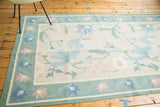 Vintage Dhurrie carpet corner, honeydew green border, pink, blue floral motifs, serrated leaves.