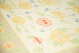 Vintage Dhurrie rug with scrolling yellow, blush, and light blue floral design.
