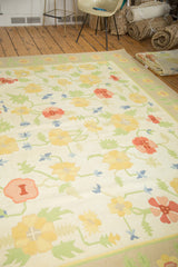 Vintage Dhurrie carpet's playful yellow, blush, and blue floral patterns with green leaves.