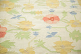 Dhurrie weave with scrolling yellow, blush, light blue, and green floral design.