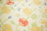 Vibrant scrolling floral pattern on a vintage Dhurrie carpet in yellow, blush, and blue.