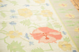 Dhurrie carpet's large scrolling floral design in blush, sunflower yellow, light blue, and green.