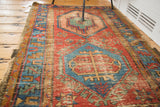 Antique Bakshaish runner with distressed pile, featuring geometric red, ocean blue, and mint green.