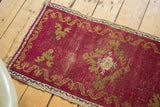 Antique Turkish Oushak mat corner with cinnabar red field, gold ribboned border, and distressed texture.