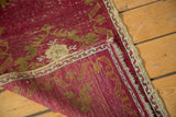 Secured side of antique Turkish Oushak rug, revealing hand knotted construction and cinnabar red.