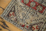 Distressed antique Oushak rug showing worn pile, geometric patterns in brick red, charcoal, ivory.