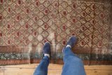 Overhead view of a distressed antique Caucasian Marsali rug's geometric lattice and worn texture.