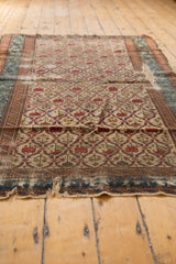 Low angle view of a distressed Caucasian Marsali rug, showing the repeating lattice design and tattered edge.