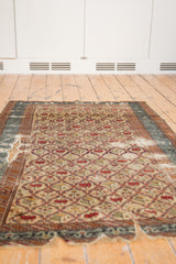 An antique Caucasian rug's storied character, with heavy tatter and a time-softened lattice design.