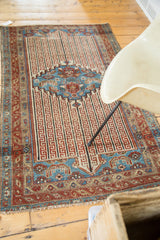 Close view of antique Malayer rug fringe, featuring ruby red border and aqua blue channels.