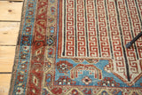 Antique Malayer rug's ruby red and aqua border, displaying etched geometric channels and distress.