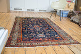 Antique Persian Malayer rug with geometric botanical motifs on a deep blue field.