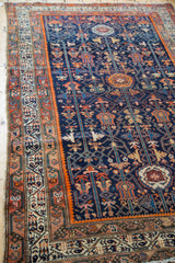 Detailed border and corner of the Malayer rug, featuring geometric shrubs in navy, orange, and saffron.