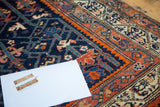 Hand-knotted navy and denim blue geometric patterns with vibrant red-orange accents.