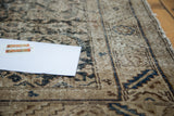 Distressed surface of the antique Hamadan rug, revealing muted earth tones and dark blue motifs.