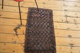 Hand-knotted plum red boteh motifs on dark indigo of this antique Belouch mat.
