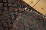 Antique Belouch rug's hand-knotted foundation showing plum boteh pattern.