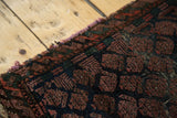 Antique Belouch rug detail: plum red boteh motifs on indigo, with secured side.