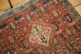 Detail of antique Malayer rug's central diamond medallion, showing pictorial animals and blush red field.