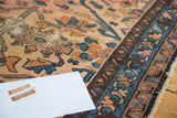 Aged border detail of an antique Lilihan rug, featuring blush, indigo, and gold floral patterns.